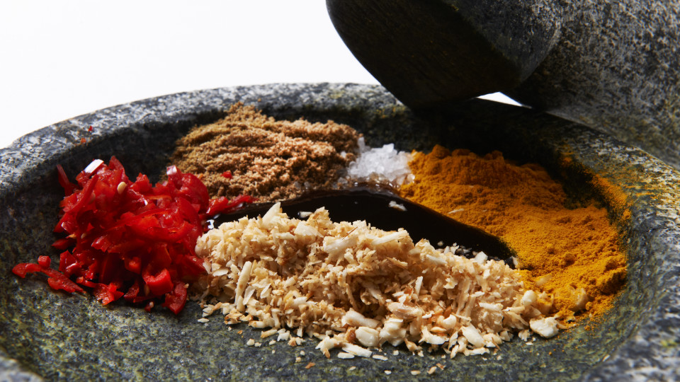 Bumbu-ingrediënten in een stenen cobek: gehakte rode peper, gemalen kemiri, kunyit, jintan en zout