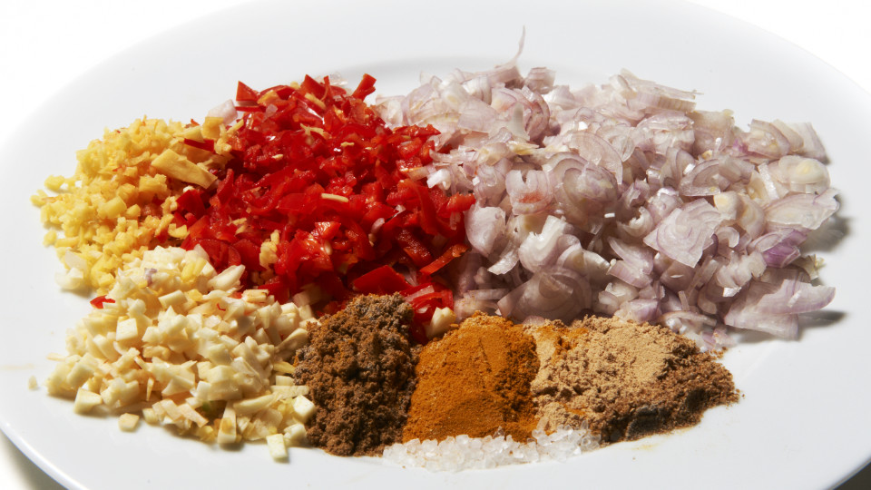 Gesneden sjalot, rode lombok, knoflook, gember en kerriepoeders