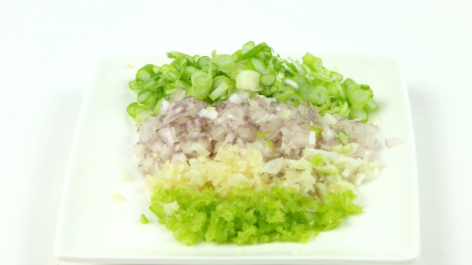 Fijngesneden bosui, sjalot, knoflook en groene rawit voor de dressing