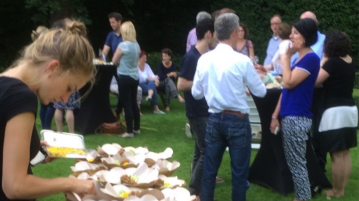 Gasten genieten van een walking dinner in de tuin