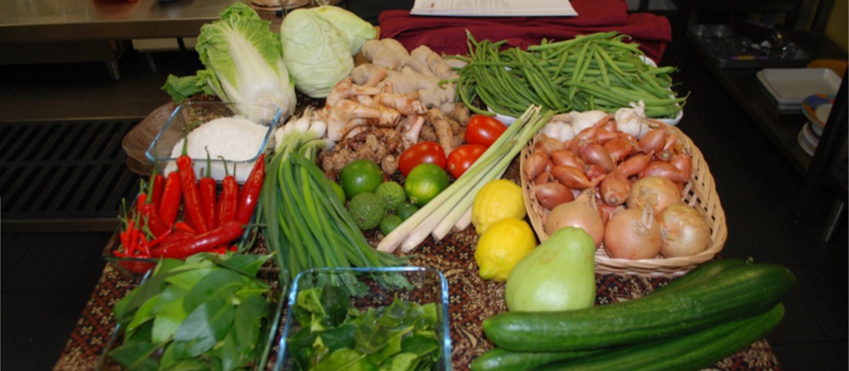 Stilleven van verse ingrediënten voor een kookworkshop: kool, peultjes, rode pepers, citroengras en garnalen