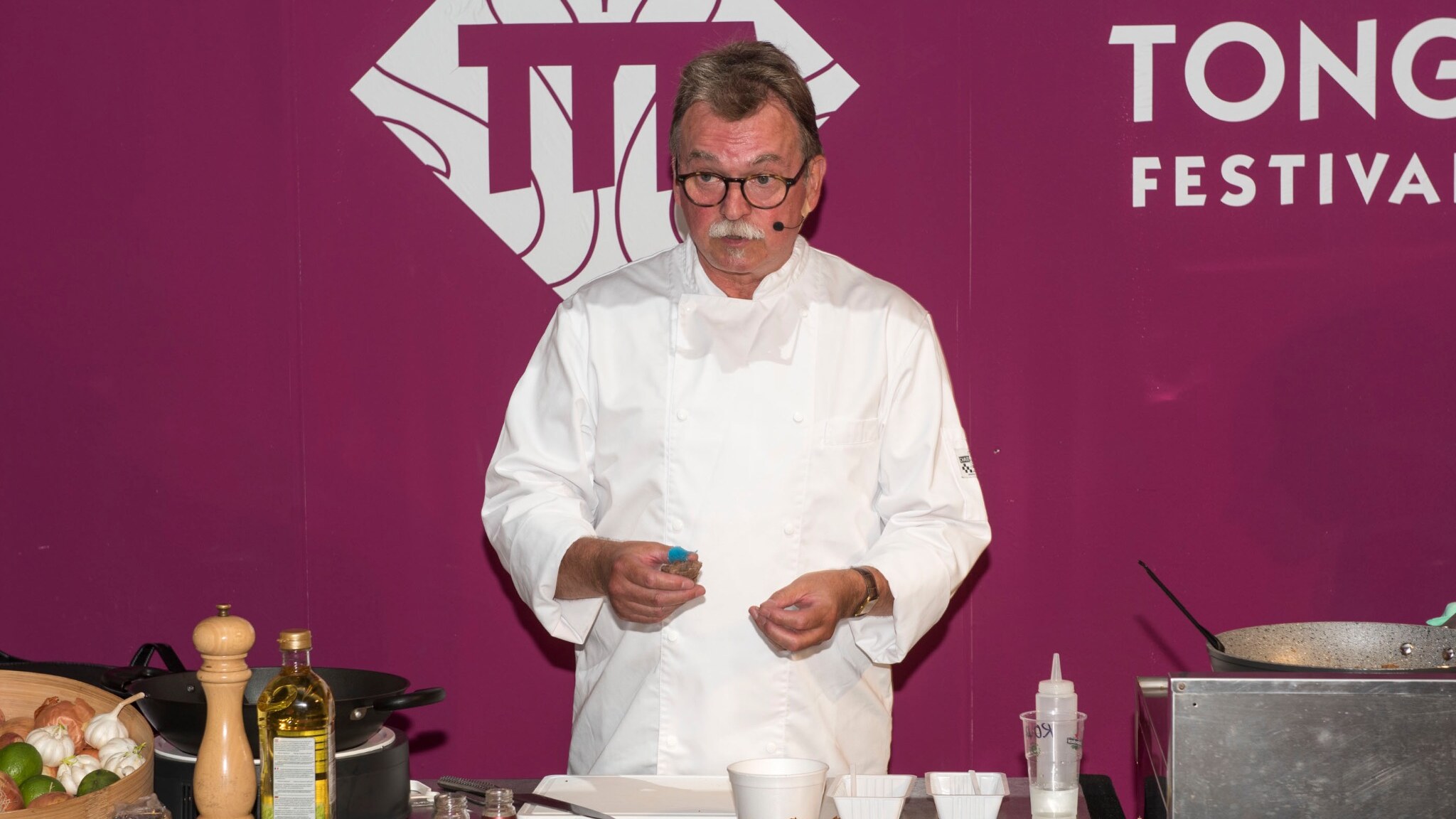 Kookdemonstratie op een festival door een kok in witte koksbuis