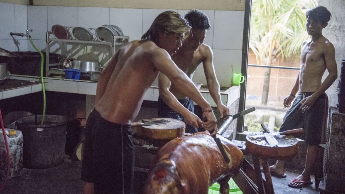Jonge mannen maken de geroosterde speenvarkens eetklaar