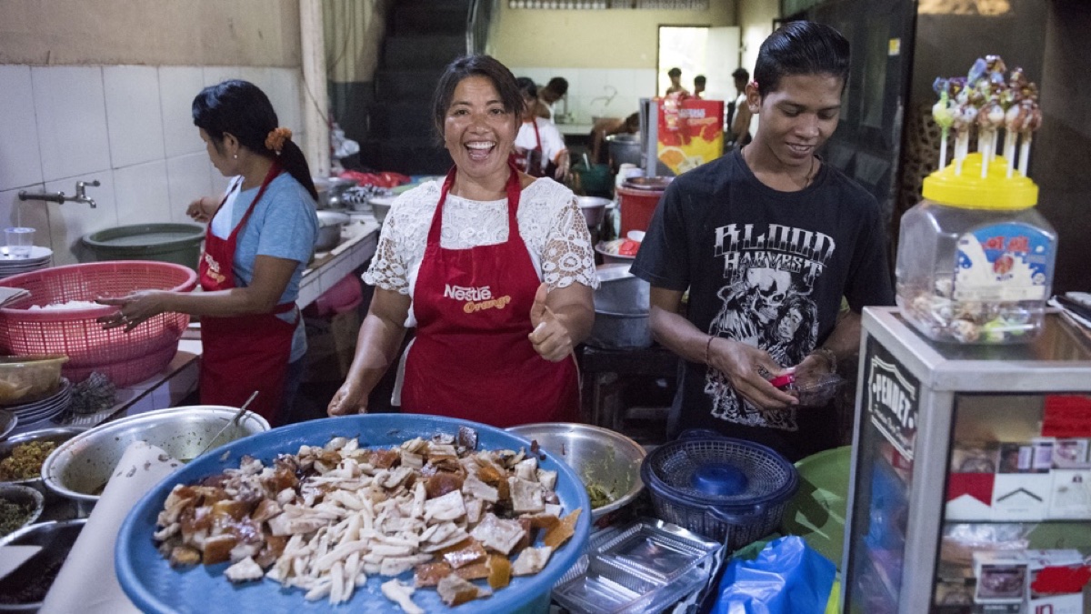 Lachende kookster met een schaal babi guling in een Balinese warung