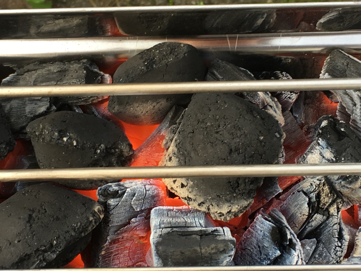 Gloeiende briketten onder het grillrooster