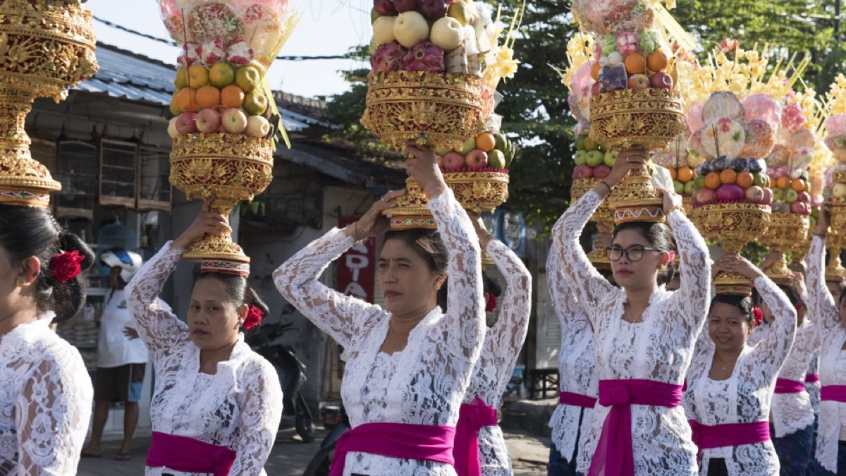 Balinese vrouwen dragen hoge offertorens op hun hoofd tijdens een processie