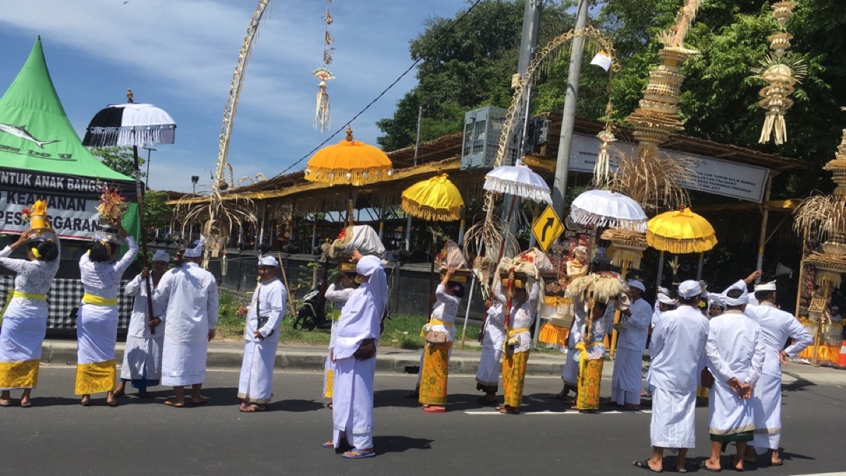 Tempelfestival op Bali met gelovigen in het wit, parasols en penjors
